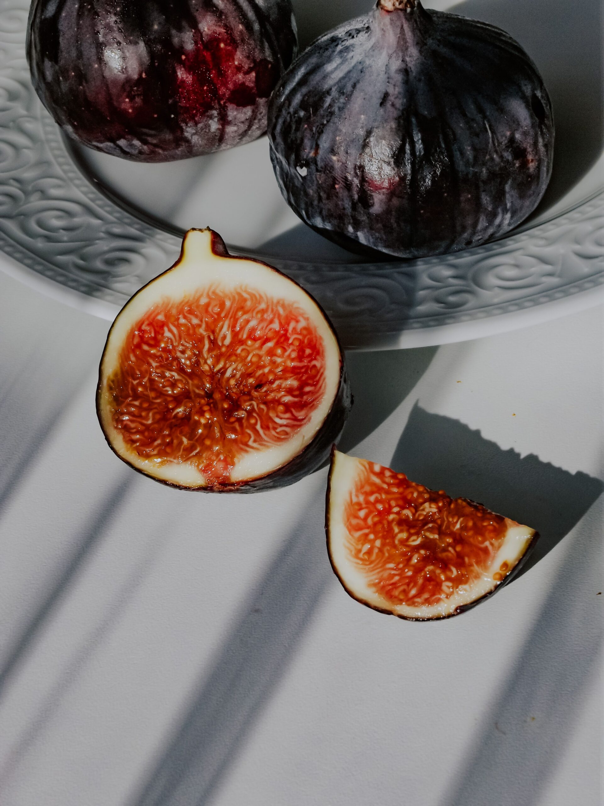 Vibrant close-up of ripe figs and slices on a decorative plate.
